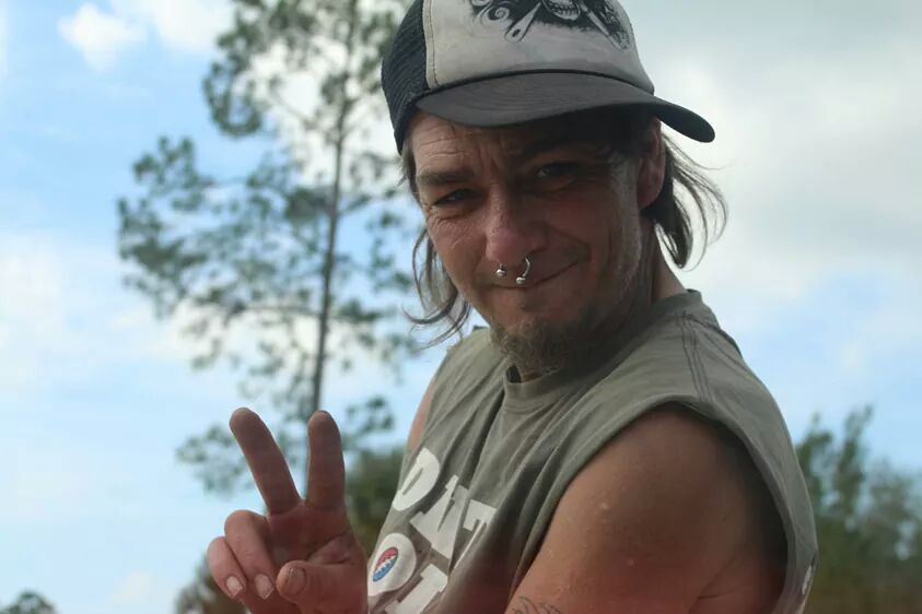 A loved one smiling outdoors with a peace sign