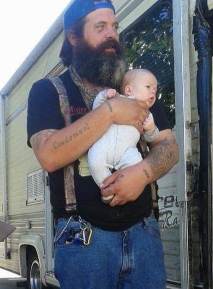 A loved one holding a baby outside by a camper