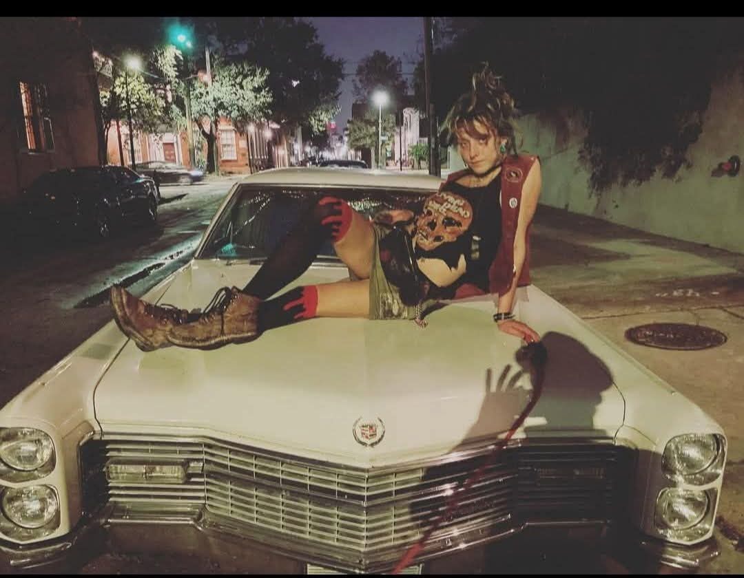 A loved one sitting on the hood of a classic car at night